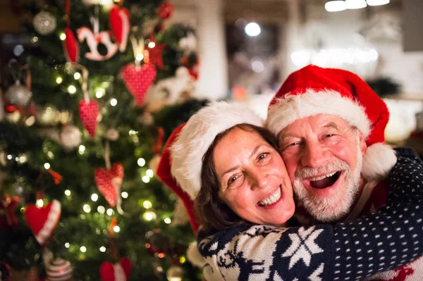 Couple aîné avec chapeaux de Père Noël au temps de Noël . — Photo