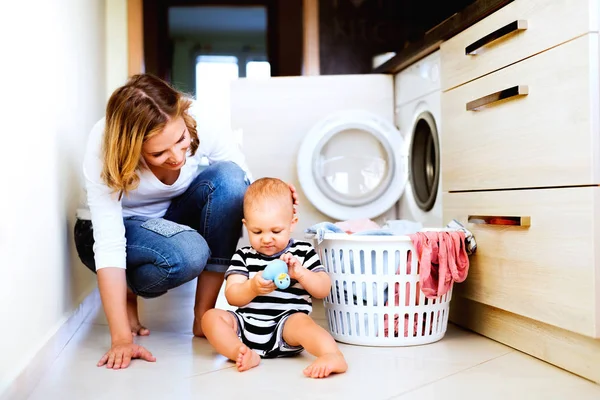 Jonge moeder met een babyjongen doen van huishoudelijk werk. — Stockfoto