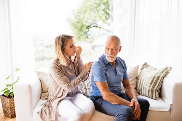 Visitante de saúde e um homem idoso durante a visita domiciliar . — Fotografia de Stock