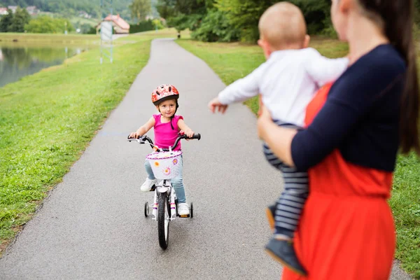 Liten flicka med sin mor och bror i naturen. — Stockfoto