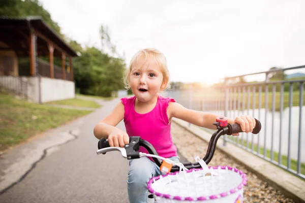 Κοριτσάκι είναι το ποδήλατο στη φύση δίπλα στη λίμνη. — Φωτογραφία Αρχείου