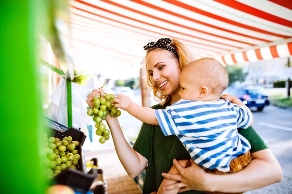 Junge Mutter mit ihrem kleinen Jungen auf dem Freiluftmarkt. — Stockfoto