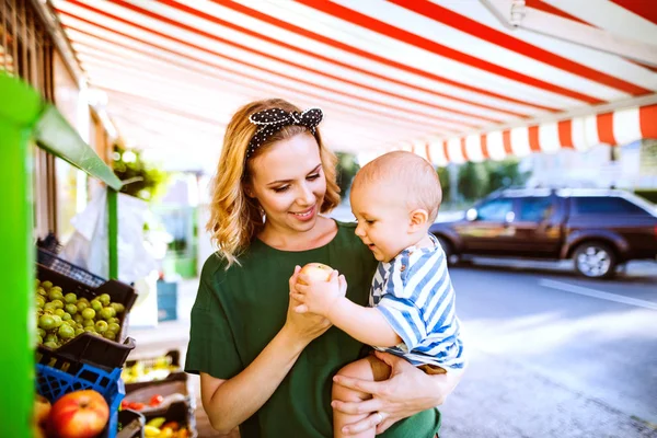 Mladá matka s její chlapeček na venkovní trh. — Stock fotografie