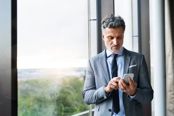 Rijpe zakenman met smartphone in een hotel. — Stockfoto