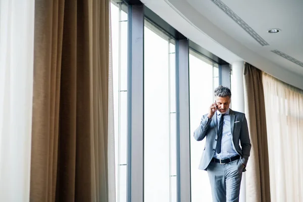Uomo d'affari maturo con smartphone in un hotel . — Foto Stock