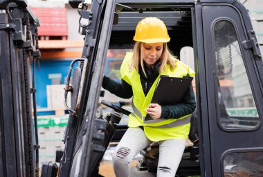 Kadın forklift kamyon şoförü bir depo dışında.