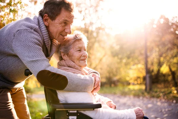 Uomo e donna anziani in sedia a rotelle nella natura autunnale . — Foto Stock