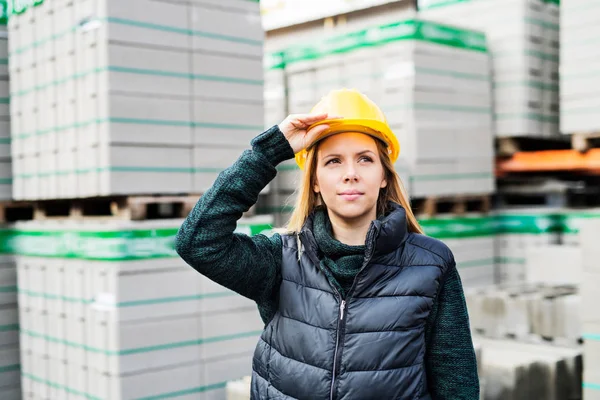 Vrouwelijke werknemer permanent buiten een magazijn. — Stockfoto