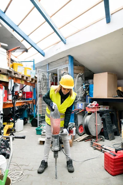 Trabalhadora com martelo pneumático em um armazém . — Fotografia de Stock