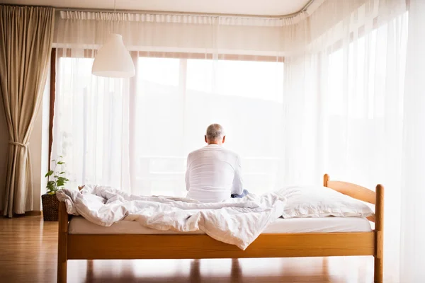 Uomo anziano seduto sul letto a casa . — Foto Stock