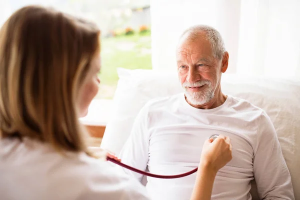 Visitatore di salute e un uomo anziano durante la visita a casa . — Foto Stock