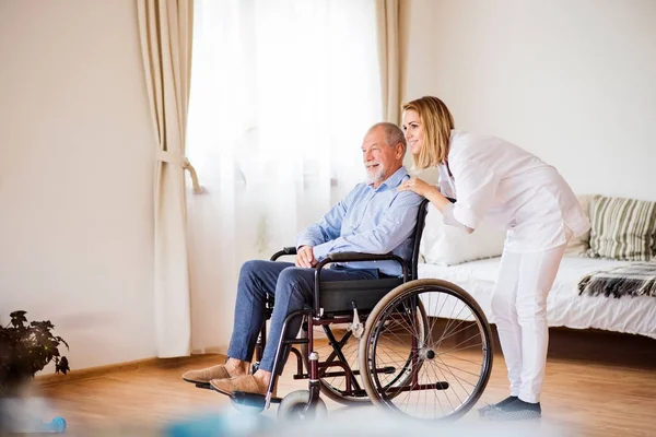 Enfermeira e idoso em cadeira de rodas durante visita domiciliar . — Fotografia de Stock