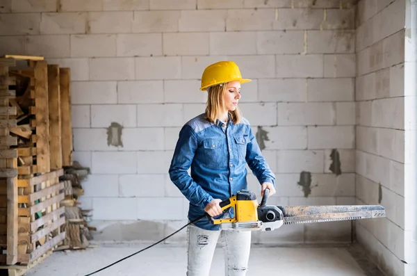 Young woman worker with saw on the construction site. — Stock Photo, Image