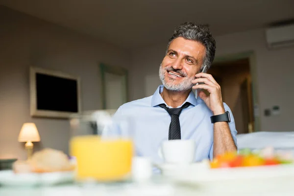Mature businessman with smartphone in a hotel room. — Stock Photo, Image