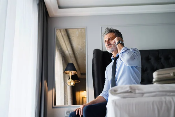 Mature businessman with smartphone in a hotel room. — Stock Photo, Image