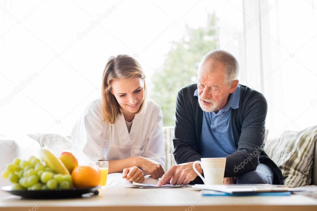 Health visitor and a senior man with tablet during home visit.