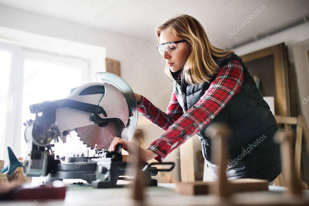 Young woman worker in the carpenter workroom.