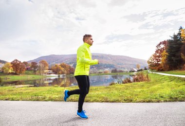 Renkli sonbahar doğa parkında çalışan genç atlet.