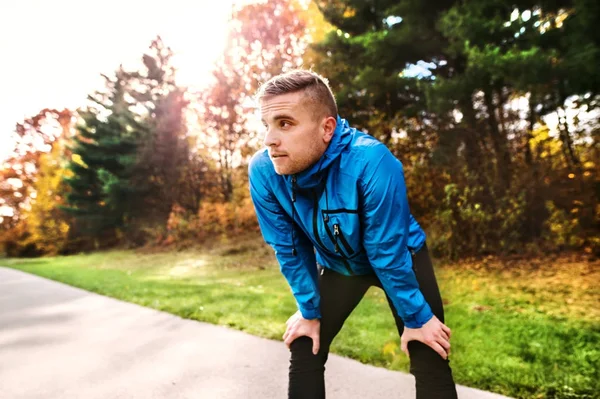 Jeune coureur dans le parc d'automne debout sur un sentier en béton . — Photo