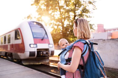 Genç anne bebekle tren ile seyahat eden.
