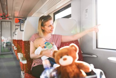 Genç anne bebekle tren ile seyahat eden.