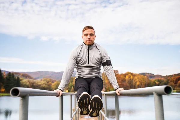 Ung man med smartphone gör övning i park. — Stockfoto