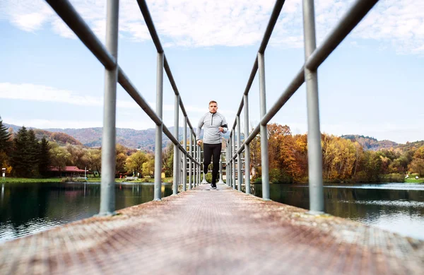 Joven atleta con smartphone corriendo en el parque en otoño . —  Fotos de Stock