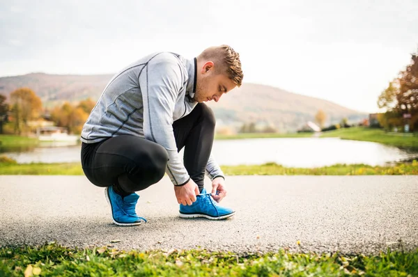 Knappe jonge runner koppelverkoop schoenveters. — Stockfoto