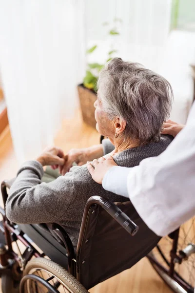 Visitante de salud y una mujer mayor durante la visita a casa . — Foto de Stock