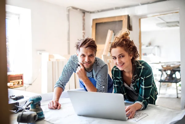 Pareja joven con portátil en el taller de carpintero . — Foto de Stock