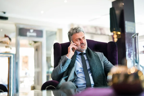 Homme d'affaires mature avec smartphone dans un salon d'hôtel . — Photo