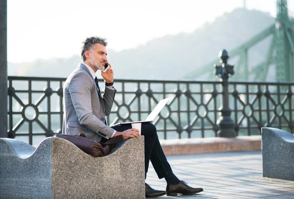 Uomo d'affari maturo con smartphone in una città . — Foto Stock