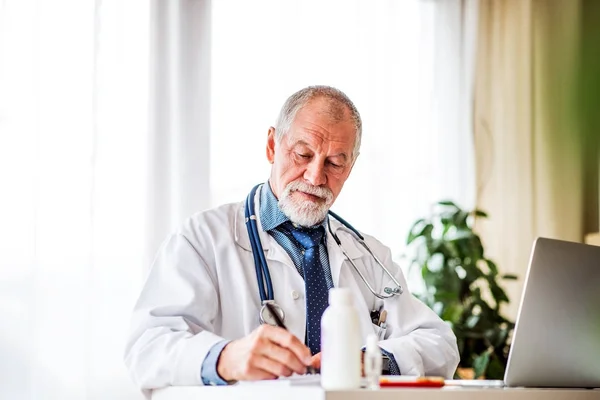 Médico senior con portátil trabajando en el escritorio de la oficina . —  Fotos de Stock