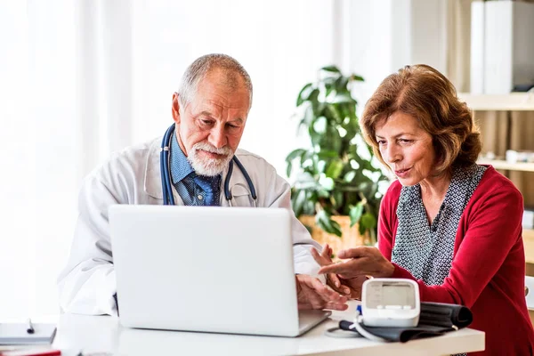 Dottore con computer portatile che parla con una donna anziana in carica . — Foto Stock