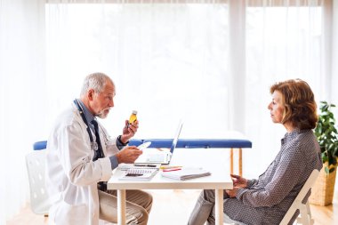 Doktor ofisinde kıdemli bir kadın konuşuyor dizüstü bilgisayar ile.