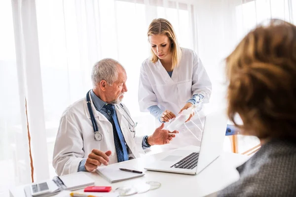 Ledande läkare undersöker en senior kvinna i office. — Stockfoto