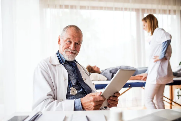Senior doctor with tablet in his office. — Stock Photo, Image