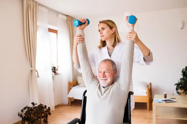 Sjuksköterska och senior mannen i rullstol under hembesök. — Stockfoto