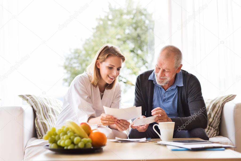 Health visitor and a senior man with tablet during home visit.