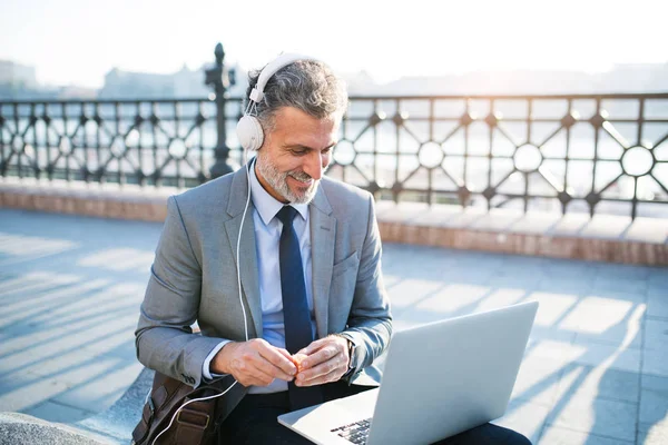 Reifer Geschäftsmann mit Laptop in der Stadt. — Stockfoto