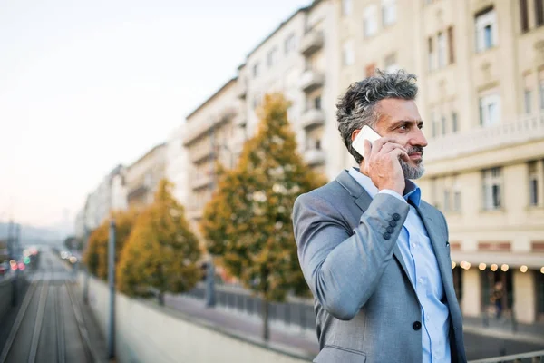 Uomo d'affari maturo con uno smartphone in una città . — Foto Stock