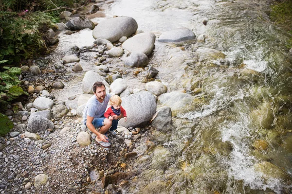 Junger Vater mit kleinem Jungen am Fluss, Sommertag. — Stockfoto