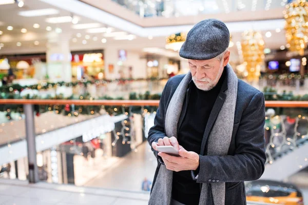 Старший мужчина со смартфоном делает рождественские покупки . — стоковое фото