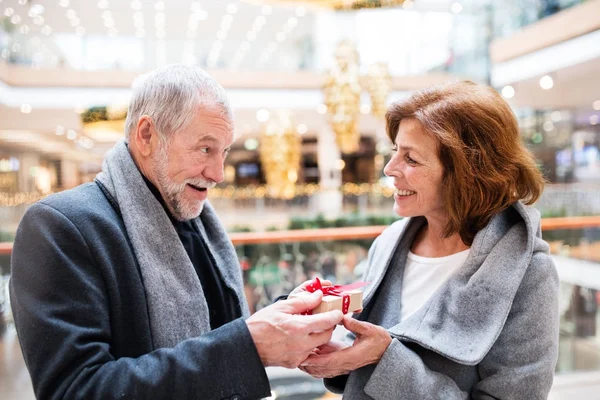 Starší pár s současnosti dělá vánoční nákupy. — Stock fotografie