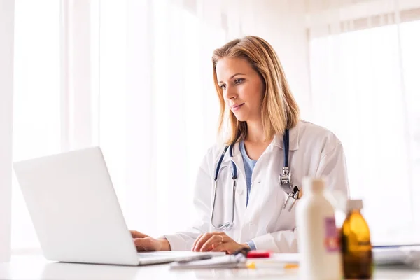 Doctora con portátil trabajando en el escritorio de la oficina . —  Fotos de Stock