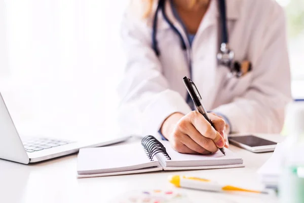 Doctora con portátil trabajando en el escritorio de la oficina . —  Fotos de Stock