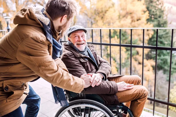 Père aîné en fauteuil roulant et jeune fils en promenade . — Photo