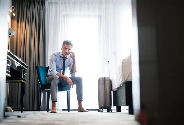 Mature businessman with smartphone in a hotel room. — Stock Photo, Image