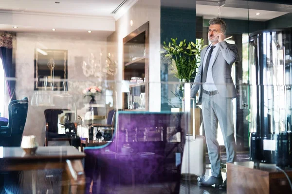 Hombre de negocios maduro con smartphone en un salón de hotel . — Foto de Stock