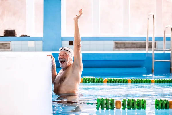 Senior man zwemmen in een overdekt zwembad. — Stockfoto